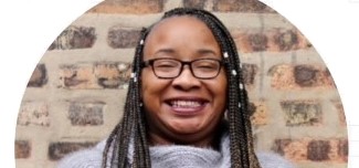 Westinghouse College Prep High School teacher Nina Hike, wearing glasses and smiling in front of a brick wall.